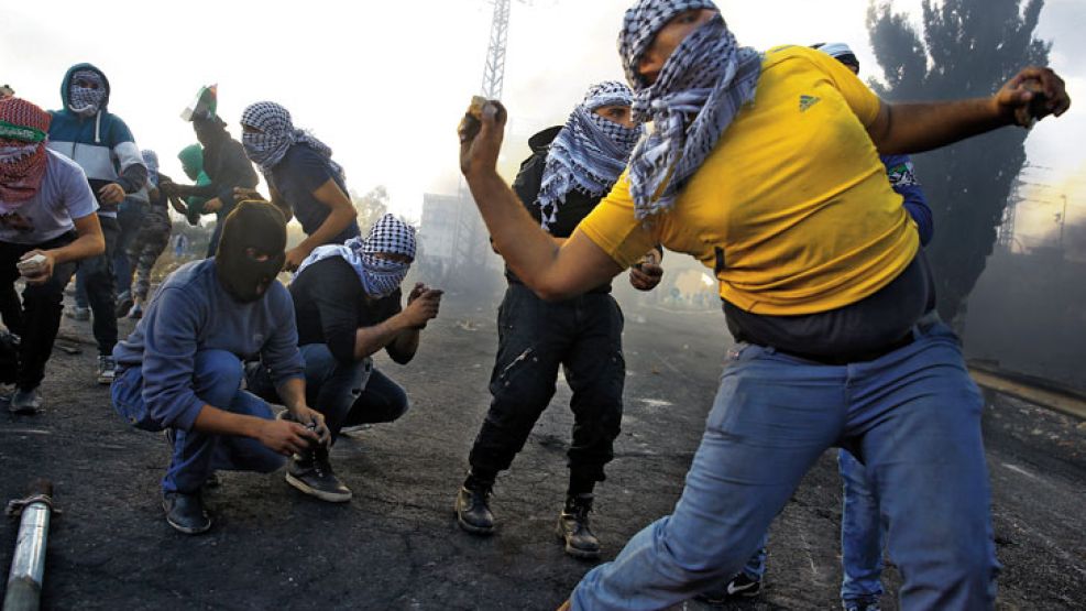 Violencia. Jóvenes palestinos arrojan piedras en la valla que separa Gaza de Israel.