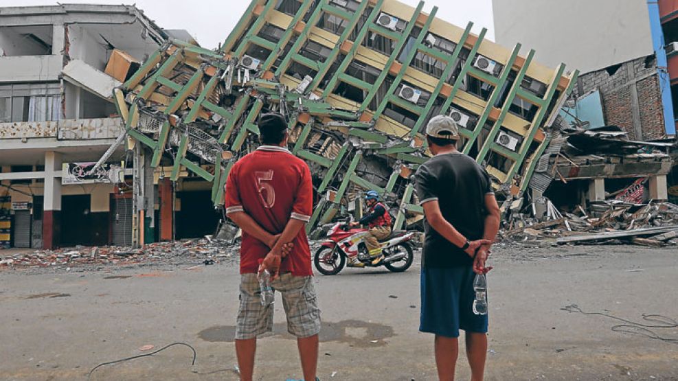 Paisaje. Dos personas contemplan los restos de un edificio que se derrumbó a causa del sismo.