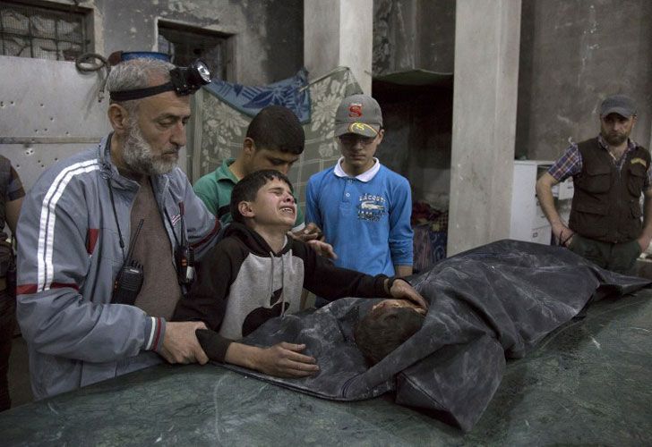 Un chico sirio es consolado mientras llora al lado del cuerpo de un pariente que murió en un ataque aéreo reportado el 27 de abril de 2016 en el vecindario de al-Soukour, en la ciudad norteña de Alepo.