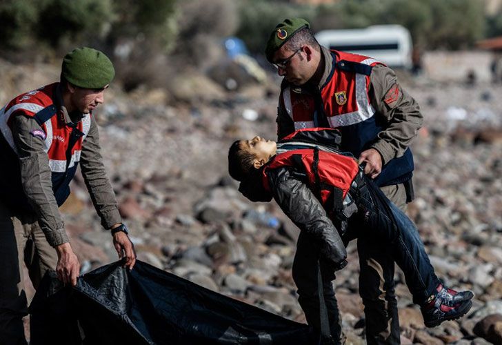 Un gendarme turco lleva el cuerpo de un niño migrante en la playa del distrito Bademli de Canakkale el 30 de enero de 2016 después de que al menos 33 inmigrantes se ahogaron cuando su barco se hundió en el mar Egeo mientras intentaba cruzar de Turquía a Grecia. Informó la agencia.