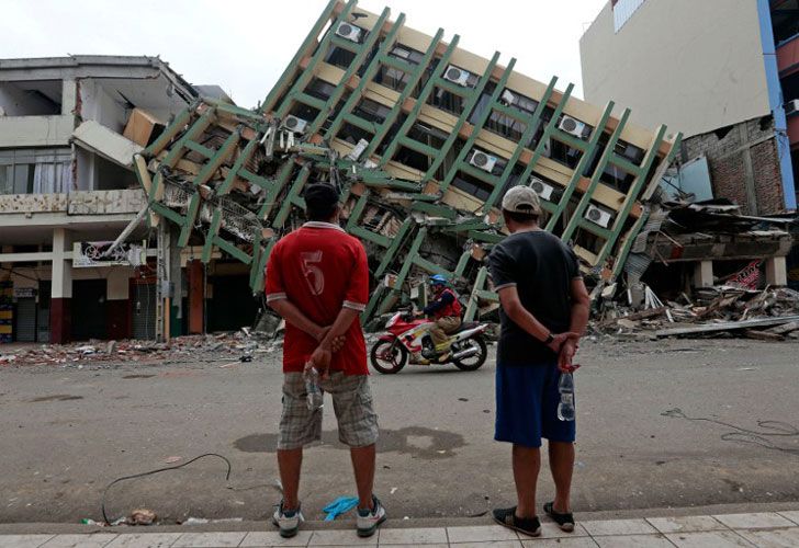 Los hombres miran un edificio destruido en la ciudad de Portoviejo, Ecuador, el 21 de abril de 2016 casi una semana después de que un poderoso terremoto golpeara el país.