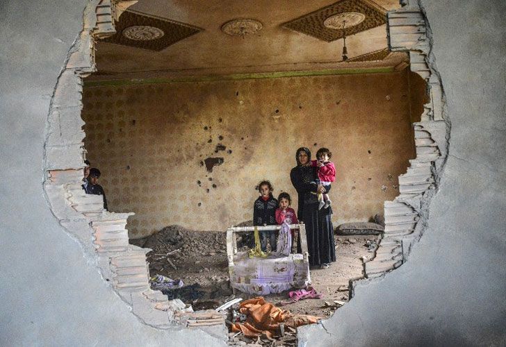 Una mujer y sus hijos están en las ruinas de una casa dañada en la ciudad kurda de Silopi, en el sureste de Turquía, cerca de la frontera con Irak, el 19 de enero de 2016.