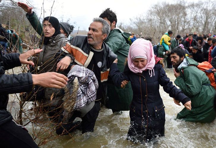 Los refugiados y los inmigrantes intentan cruzar un río en su camino a Macedonia desde un campamento improvisado en la frontera griego-macedonia, cerca del pueblo griego de Idomeni el 14 de marzo de 2016.