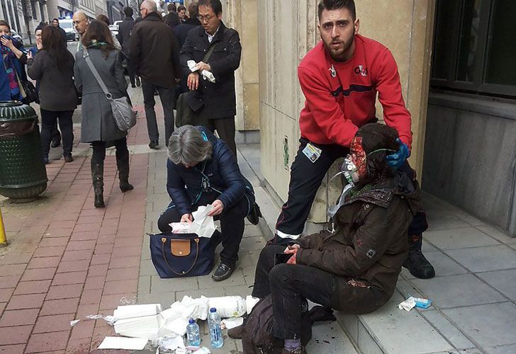 Un guardia de seguridad privado ayuda a las mujeres heridas fuera de la estación de metro Maalbeek - Maelbeek en Bruselas el 22 de marzo de 2016 después de una explosión en esta estación situada cerca de las instituciones de la UE.