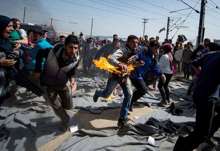 Un hombre corre después de que él intentó ponerse en el fuego durante una protesta en un campamento improvisado en la frontera Griego-Macedonia cerca de la aldea de Idomeni el 22 de marzo de 2016. 