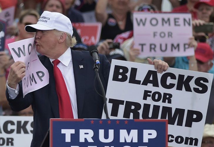 El candidato presidencial republicano Donald Trump besa una "mujer para el triunfo" cartel durante una reunión en el aeropuerto regional de Lakeland Linder en Lakeland, la Florida el 12 de octubre de 2016.