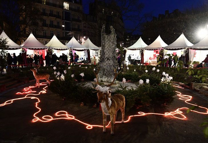 La gente mira los puestos en un mercado de Navidad cerca de la catedral de Notre Dame en París central en la víspera de Navidad, 24 de diciembre de 2016.