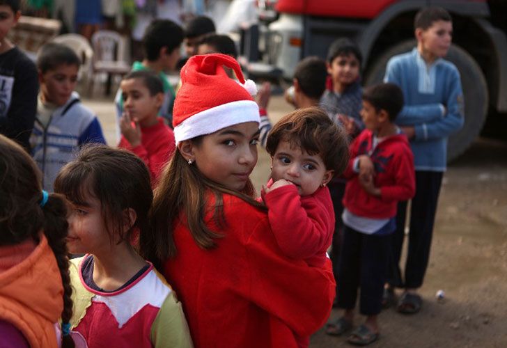 Chloe, una adolescente cristiana libanesa vestida como Santa Claus, tiene un refugiado sirio el 24 de diciembre de 2016 durante una distribución de regalos organizada por la congregación maronita "Mission de Vie" en un barrio pobre de la ciudad de Dbayeh, al norte de Beirut.