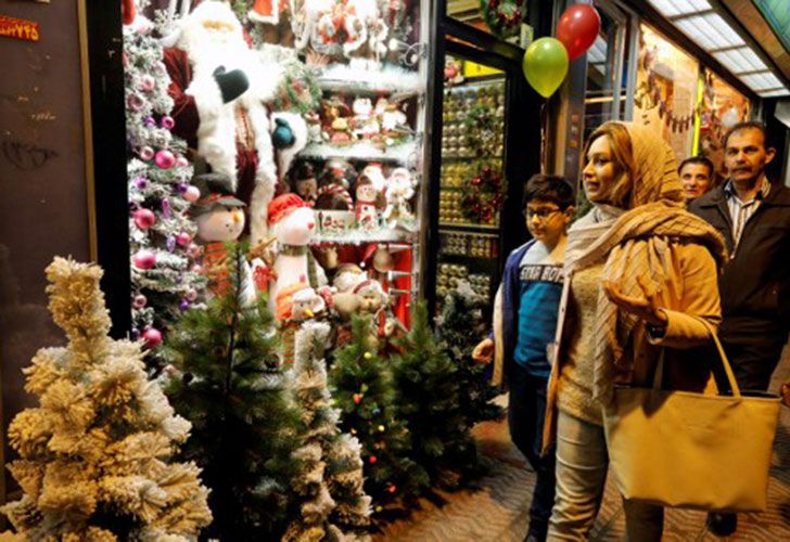 Iránes caminan pasado la decoración de Navidad en una tienda en la capital Teherán el 24 de diciembre de 2016, en vísperas de Navidad.