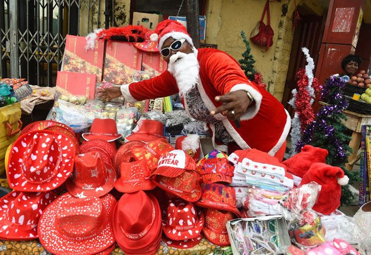 Una vendedora femenina vestida con las tradiciones de regalos de Navidad muestra sus mercancías de Navidad en Lagos, el 24 de diciembre de 2016. Los nigerianos están haciendo compras de último minuto para celebrar la Navidad a pesar de la recesión económica que ha dado lugar al alto costo de artículos de regalo, Decorativos y alimentos en todo el país.