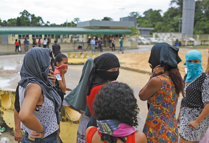 Cubiertas. Familiares de los reclusos se tapan el rostro, frente a la puerta del penal de Manaos, donde el domingo pasado murieron 56 personas.