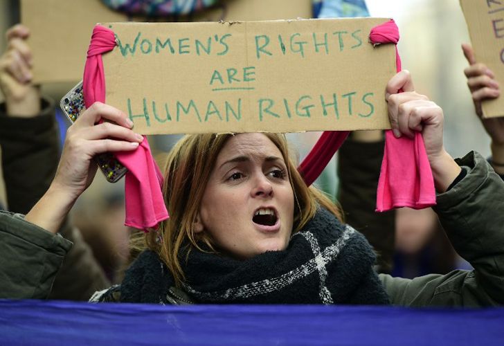 La gente marcha sosteniendo carteles en el centro de Barcelona el 21 de enero de 2017 en una marca de solidaridad para el mitin político que promueve los derechos y la igualdad para las mujeres, Marcha de la Mujer en Washington, que tiene lugar hoy en la capital de EE.UU.