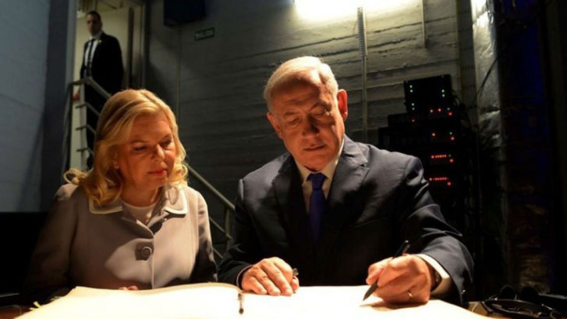 In this picture released by the Israeli government, Israeli Prime Minister Benjamin Netanyahu and his wife Sara sign the visitors book at the AMIA Jewish community centre in Buenos Aires on Monday. The bombing of the Argentine-Israeli Mutual Association in downtown Buenos Aires killed 85 people in 1994 and remains unsolved.
