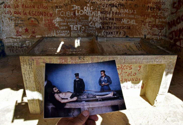 A journalist places in Vallegrande, Bolivia, on September 30, 2017 a copy of a picture taken on October 10, 1967 by AFP journalist Marc Hutten of the body of Argentine-born guerrilla leader Ernesto "Che" Guevara in front of the same laundry sink where he was placed to remain exposed one day after he was killed. Guevara was executed upon capture on the eve in La Higuera, 74 km from Vallegrande and taken to Vallegrande to be publicly exposed. AIZAR RALDES / AFP