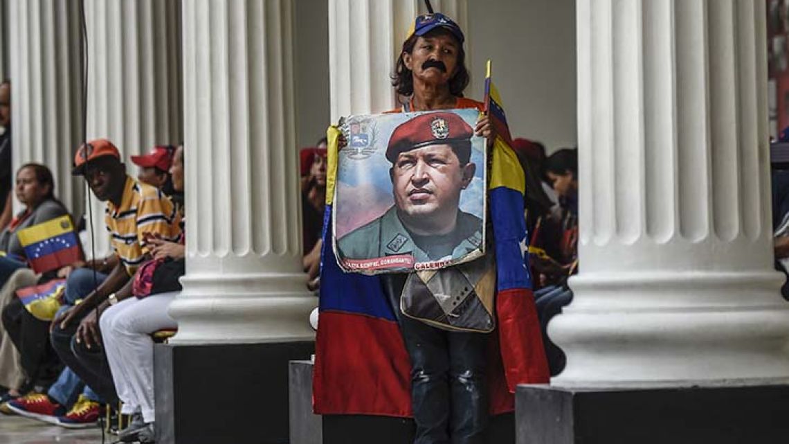 Supporters of Venezuelan president Nicolás Maduro holds a photo of the deceased former president Hugo Chávez outside the National Assembly in Caracas.