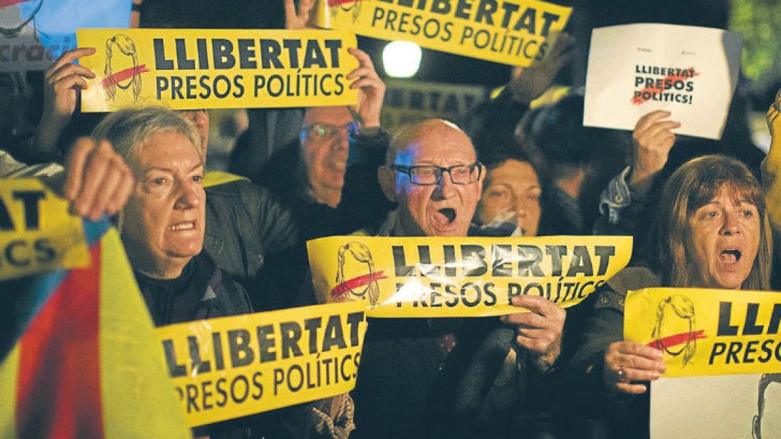 Demonstrators holding banners reading in Catalan “Freedom for the political prisoners” gather outside the Catalonian Parliament to protest against the decision to jail ex-members of the Catalan government.