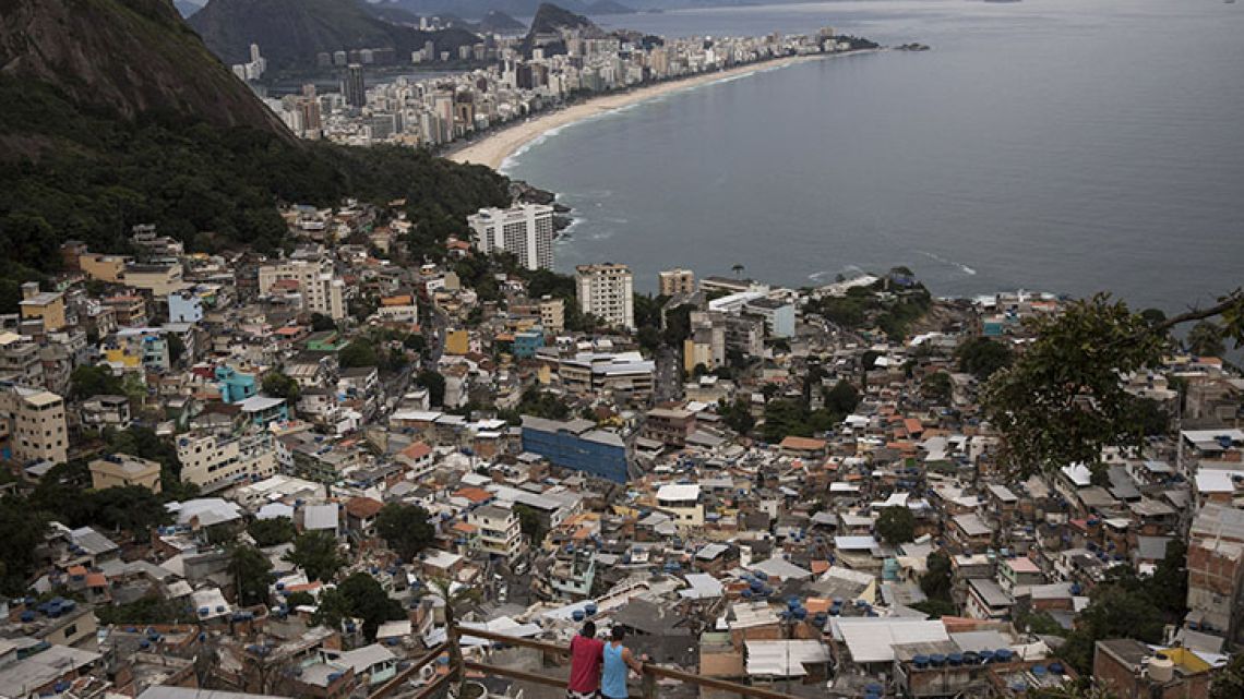 People overlook Rio de Janeiro from the Vidigal slum. Opening the hillside favelas to tourists seemed like a winning idea: they get breathtaking views, the slum residents could cash in, and foreign visitors would see another part of the city, but soaring violence has rekindled a concern about safety.