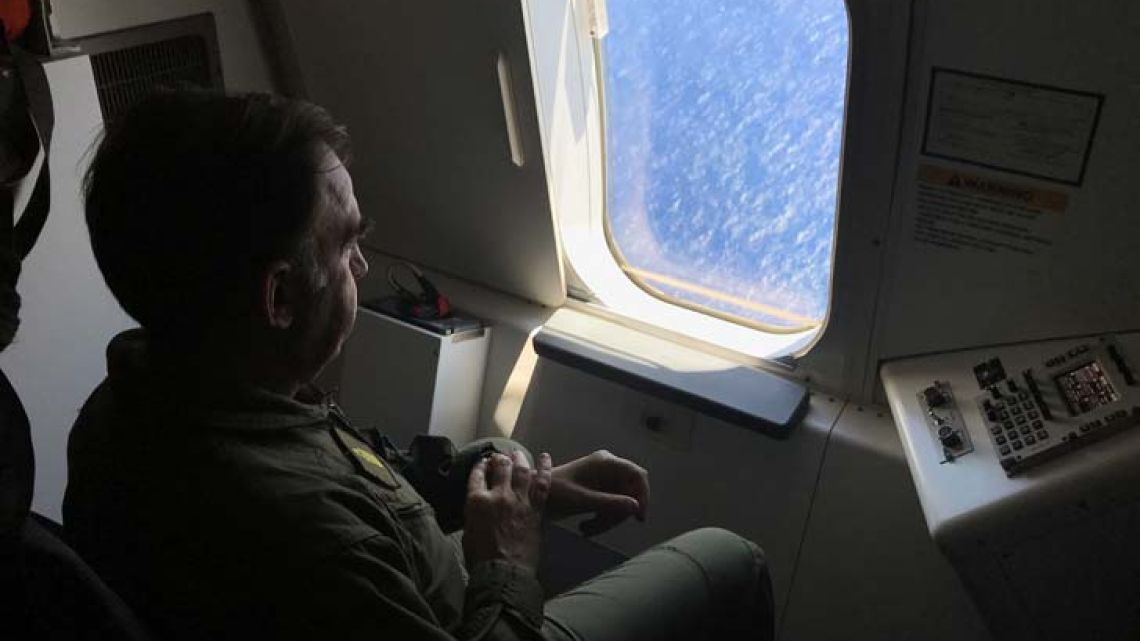 A member of the Argentine Navy looks out the window of a P8-A Poseidon aircraft of the US Navy Patrol and Reconnaissance Wing (CPRW) 11 as it assists the Argentine military in their search for the missing submarine ARA San Juan.