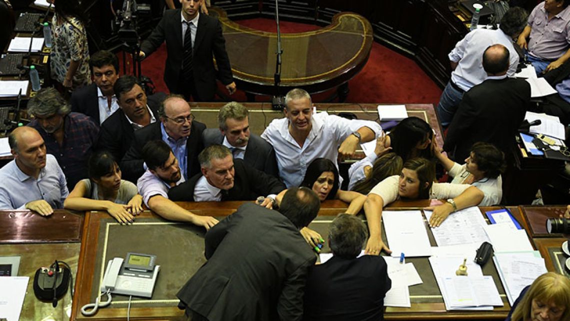 Lawmakers huddle around speaker Emilio Monzó in the middle of a scandalous session of Congress over the ruling Cambiemos coalition's pension reform package.