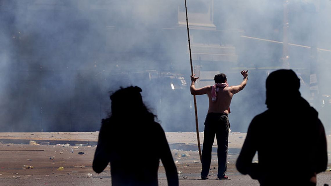 A protester armed with a stick taunts police during clashes in Buenos Aires. Argentine police clashed Thursday with demonstrators protesting reforms to the retirement and pension system. 