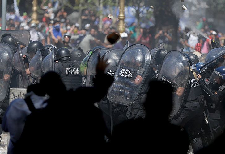 La policía se cubre de las piedras lanzadas por los manifestantes durante una protesta contra una medida de reforma de previsiones