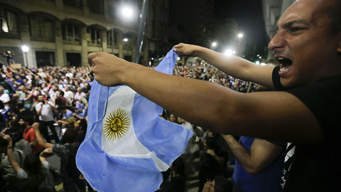 A demonstrator waves an Argentine flag as a crowd marches to the Congress to protest against a pension reform in the capital.