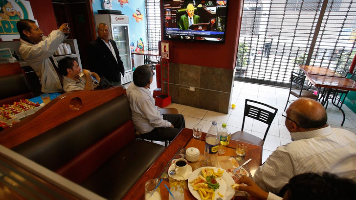 Customers eat breakfast in a restaurant as they watch Peru's President Pedro Pablo Kuczynski on a TV screen in Lima, Peru, Thursday, Dec. 21, 2017. Kuczynski is facing an impeachment vote following revelations that his private consulting business received money from the Brazilian construction company implicated in Latin America's biggest corruption scandal. (AP Photo/Karel Navarro)