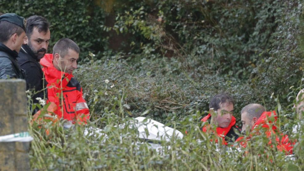 Efectivos de la Guardia Civil y bomberos trasladan en una camilla los restos del cadáver encontrado en una nave industrial en la parroquia de Asados, en Rianxo (A Coruña)