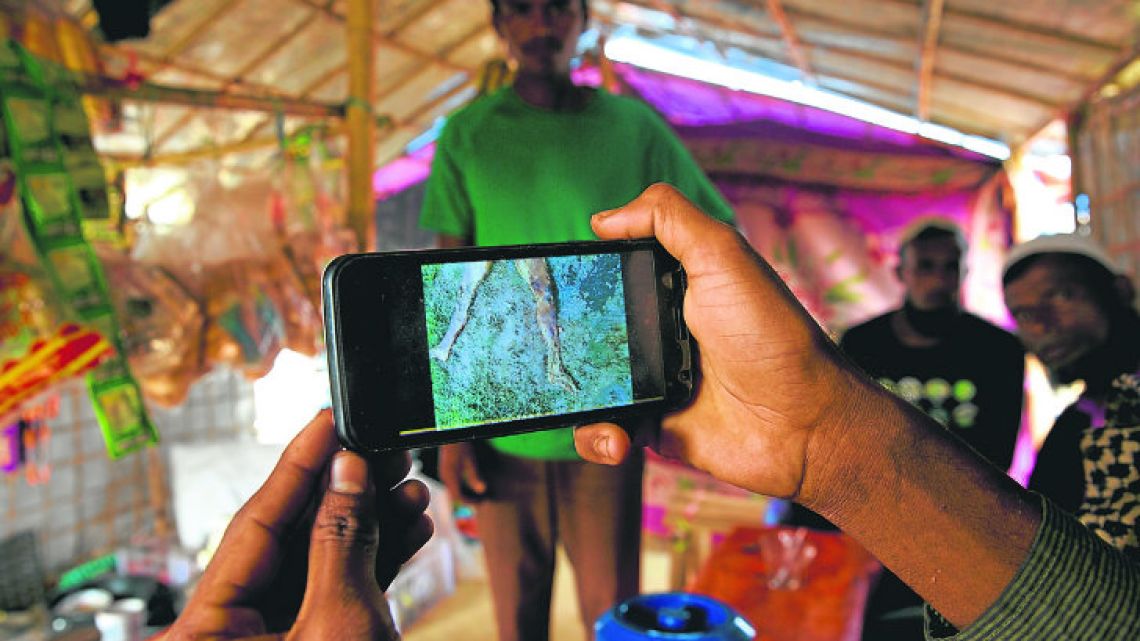 Rohingya Muslim refugee Mohammad Karim, 26, shows a mobile phone video of Gu Dar Pyin’s massacre inside his kiosk at the Kutupalong refugee camp, in Bangladesh. On September 9, a villager from Gu Dar Pyin captured three videos of mass graves, time-stamped between 10.12am and 10.14am, when he said soldiers chased him away.