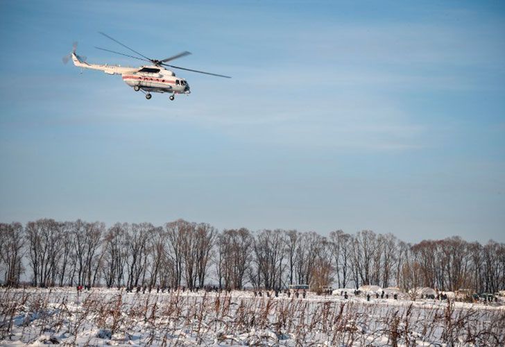 Un helicóptero se lleva los cuerpos de las víctimas mientras los rescatadores del Ministerio de Emergencia trabajan en el lugar de un accidente aéreo ocurrido el día anterior en el distrito de Ramensky, en las afueras de Moscú