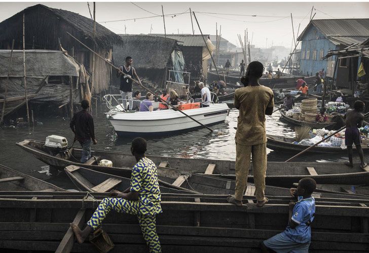 Lagos Waterfront Under Threat – La ribera de Lagos bajo amenaza: Un barco con expatriados de Lagos Marina se dirige a través de los canales de la comunidad de Makoko, un antiguo pueblo de pescadores que se ha convertido en un enorme asentamiento informal, a orillas de Lagos Lagoon, en Nigeria. La imagen fue tomada por Jesco Denzel.