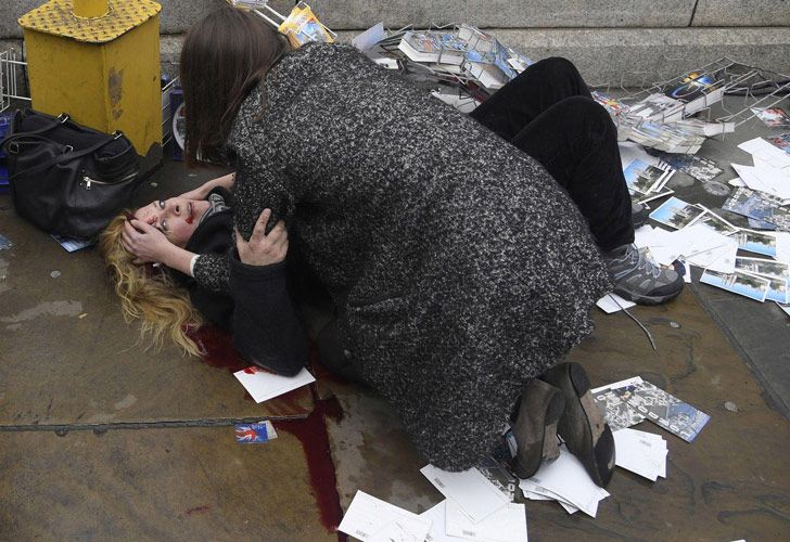 Witnessing the Immediate Aftermath of an Attack in the Heart of London – Atestiguando la Inmediata Posterioridad de un Ataque en el Corazón de Londres. Toby Melville muestra a un transeúnte consuela a una mujer herida después de que Khalid Masood condujera su automóvil contra peatones en el puente Westminster en Londres, Reino Unido, matando a cinco e hiriendo a otros muchos.