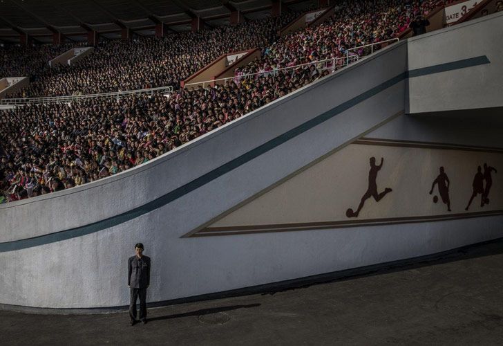 North Korea – Corea del Norte: una multitud espera la salida del Maratón de Pyongyang en el Estadio Kim Il-sung, mientras que un oficial vigila la salida, en Pyongyang, Corea del Norte. 