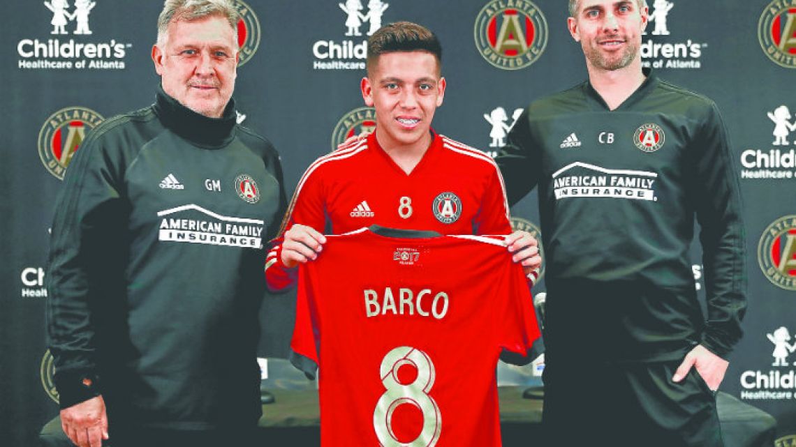 Ezequiel Barco holds his Atlanta United MLS shirt up with the club’s vice-president and technical director and head coach.