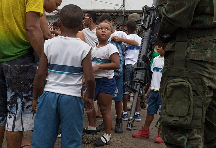 Una joven estudiante observa a un marine brasileño mientras ella y sus compañeras de clase son inspeccionadas durante una operación sorpresa en el barrio marginal de Kelson en Río de Janeiro, Brasil.