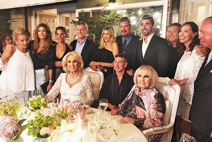 Rodeada. (De pie y de izq. a der.) Marcela Tinayre, Juliana Awada, Juana Viale, Macri, Guillermina Valdes, Tinelli, Ignacio Viale (h), Adrián Suar, Eugenia Vidal y Daniel Funes de Rioja; (sentados) Mirtha, Julio Bocca y Silvia Legrand. Juliana Awada, de plata y negro; llevó a sus dos hijas, Valentina Barbier –compañera de colegio de Ambar, hija de Juana Viale y nieta de Piero– y Antonia Macri. 