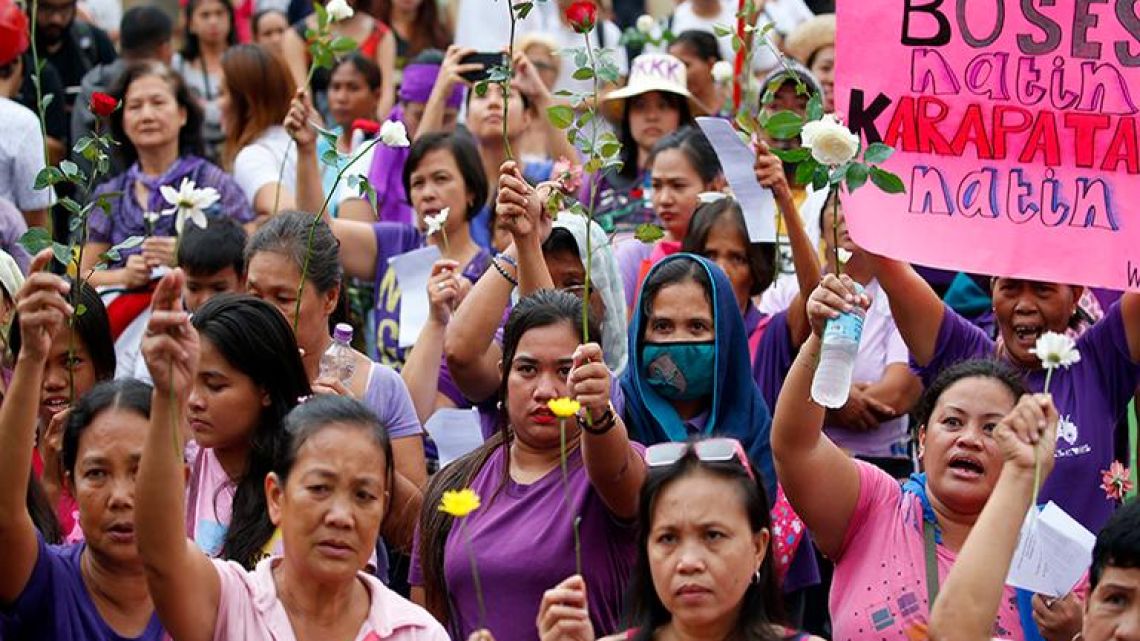 Protesters raise flowers during a rally to mark International Women's Day Thursday, March 8, 2018 in Manila, Philippines. Hundreds of women activists in pink and purple shirts protested against President Rodrigo Duterte in the Philippines on Thursday, as marches and demonstrations in Asia kicked off International Women’s Day. The sign reads "Our Voice, Our Rights!"