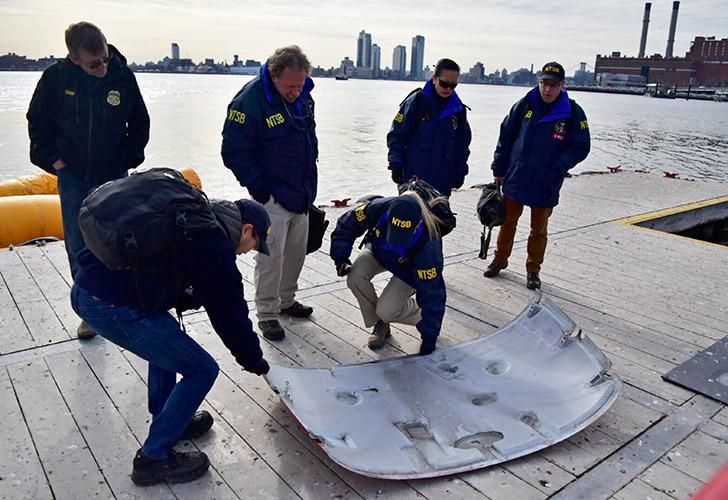 Investigadores trabajan en la escena de un helicóptero que se estrelló en el East River de Nueva York el domingo por la noche.