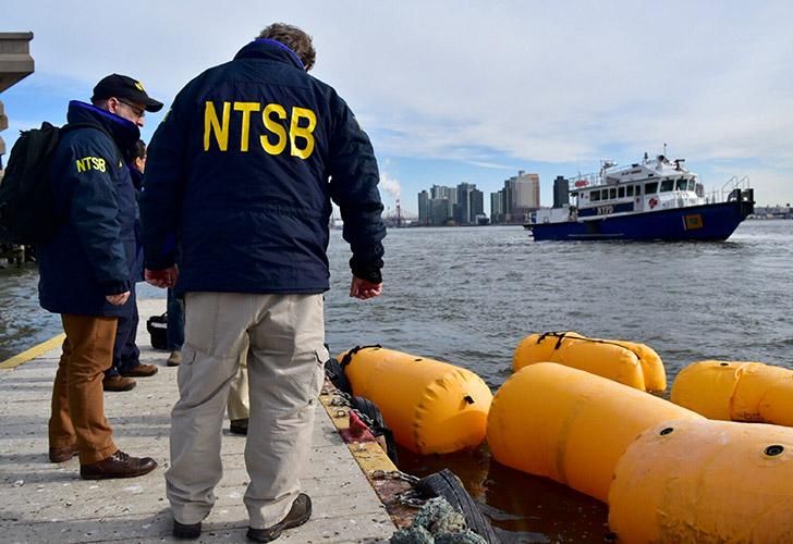 Investigadores trabajan en la escena de un helicóptero que se estrelló en el East River de Nueva York el domingo por la noche.