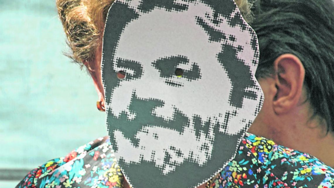 Former Brazil president Dilma Rousseff wears a mask with the face of jailed PT leader Luiz Inácio Lula da Silva.