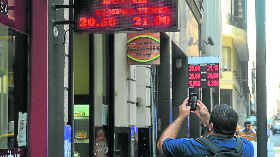 A passerby takes a photograph of the peso-dollar exchange rate outside a bureaux de change in Buenos Aires yesterday.