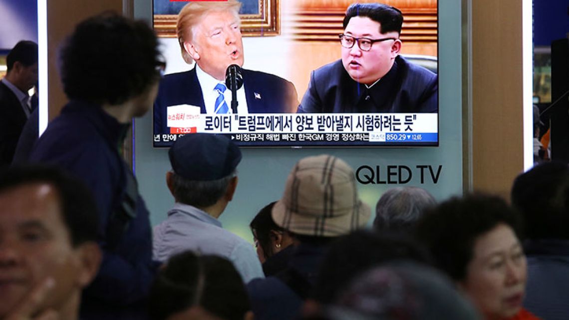 People watch a TV screen showing file footage of US President Donald Trump, left, and North Korean leader Kim Jong Un during a news program at the Seoul Railway Station in Seoul, South Korea, Wednesday, May 16, 2018.