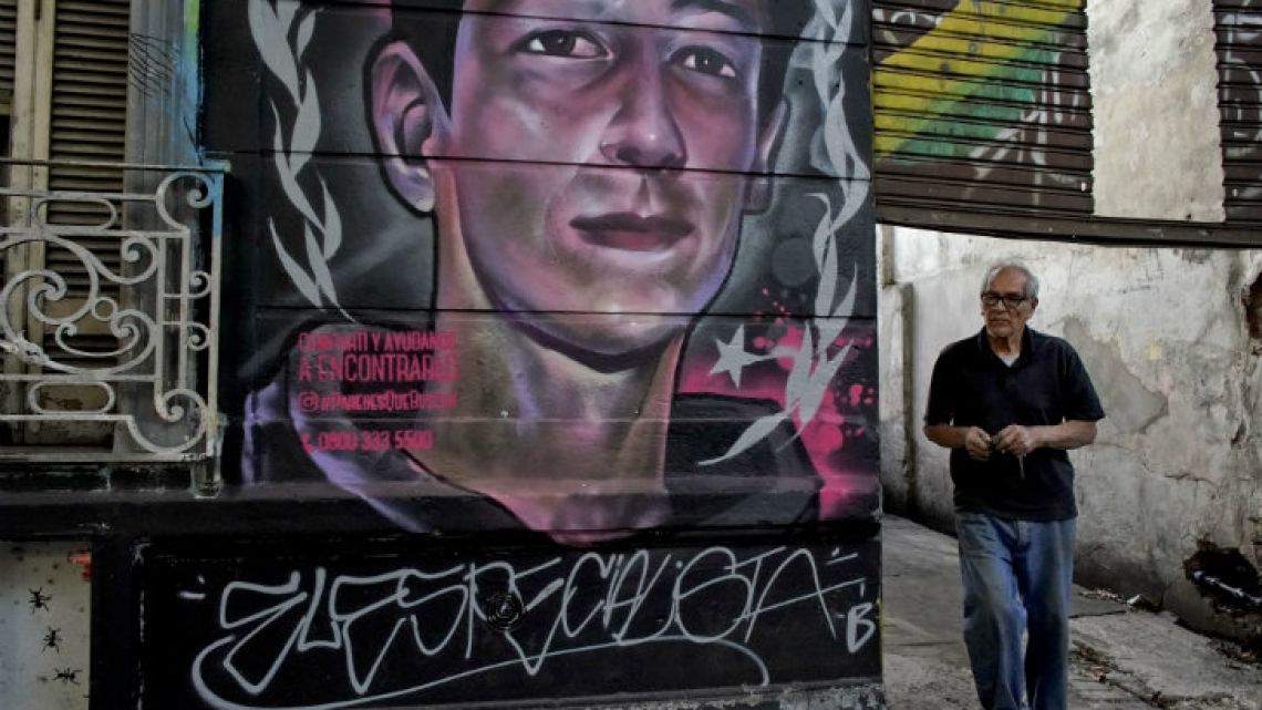A man walks by a mural of Enzo Vallejos, a 16-year-old teenager who has been missing since last year in Buenos Aires..