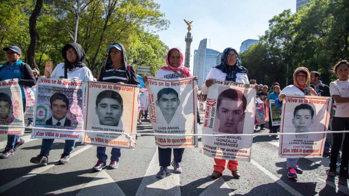 In this May 26, 2018 file photo, people display the faces of the 43 missing students during a protest to raise awareness of the students who went missing nearly four years ago, in Mexico City. The rural college students mysteriously vanished on September 26, 2014 in Iguala when they were interrupted on their way to demonstration by police. On June 4, 2018, a federal court in Mexico ordered that the investigation into the 2014 disappearance of 43 college students be done again under the supervision of a truth commission.