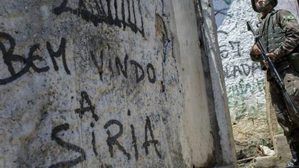 A Brazilian soldier patrols the Rocinha favela in Rio de Janeiro, Brazil. The graffiti that reads in Portuguese "Welcome to Syria."
