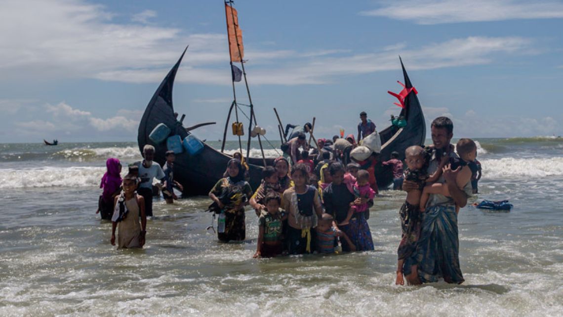 A Rohingya man carries two children to shore in Shah Porir Dwip, Bangladesh, after they arrived on a boat from Myanmar. The UN refugee agency says nearly 69 million people who have fled war, violence and persecution were forcibly displaced last year, a new record for the fifth straight year. 