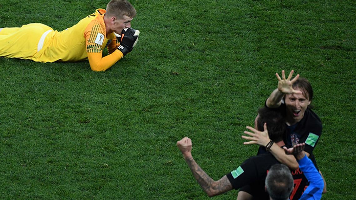 England's goalkeeper Jordan Pickford reacts after losing the Russia 2018 World Cup semi-final football match between Croatia and England at the Luzhniki Stadium in Moscow, while Croatia captain Luka Modric leads the celebrations.