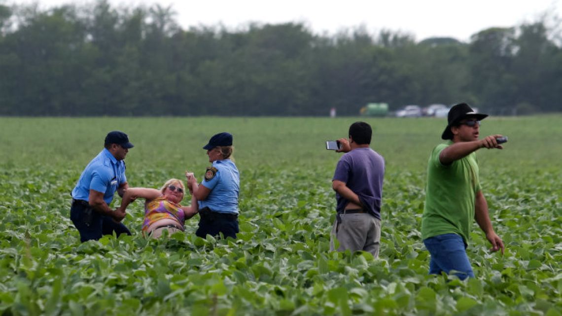 Environmentalist Sofia Gatica is arrested by police officers and soybean field owner Alejandro Dalmasso (right) tries to throw other demonstrators out.