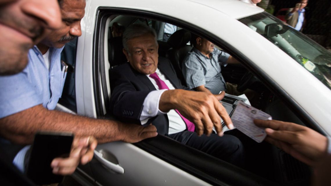 In this July 11, 2018 photo, Mexico's President-elect Andrés Manuel López Obrador receives a note from a man, as he leaves his headquarters in the Roma neighbourhood of Mexico City. Each day hundreds of Mexicans crowd outside the white, two-story offices of López Obrador, bearing handwritten notes, medical records, retirement papers and other documents, in hopes he can help with everything from boosting pensions to clemency for a jailed loved one or even offer a job.
