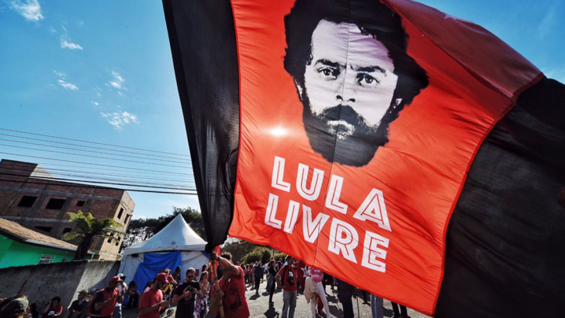 A supporter of former Brazilian president Luiz Inácio Lula da Silva waves a banner decorated with his image.